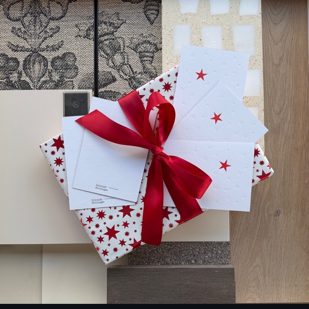 Weihnachtspost 2025 mit roter Schleife auf Materialcollage